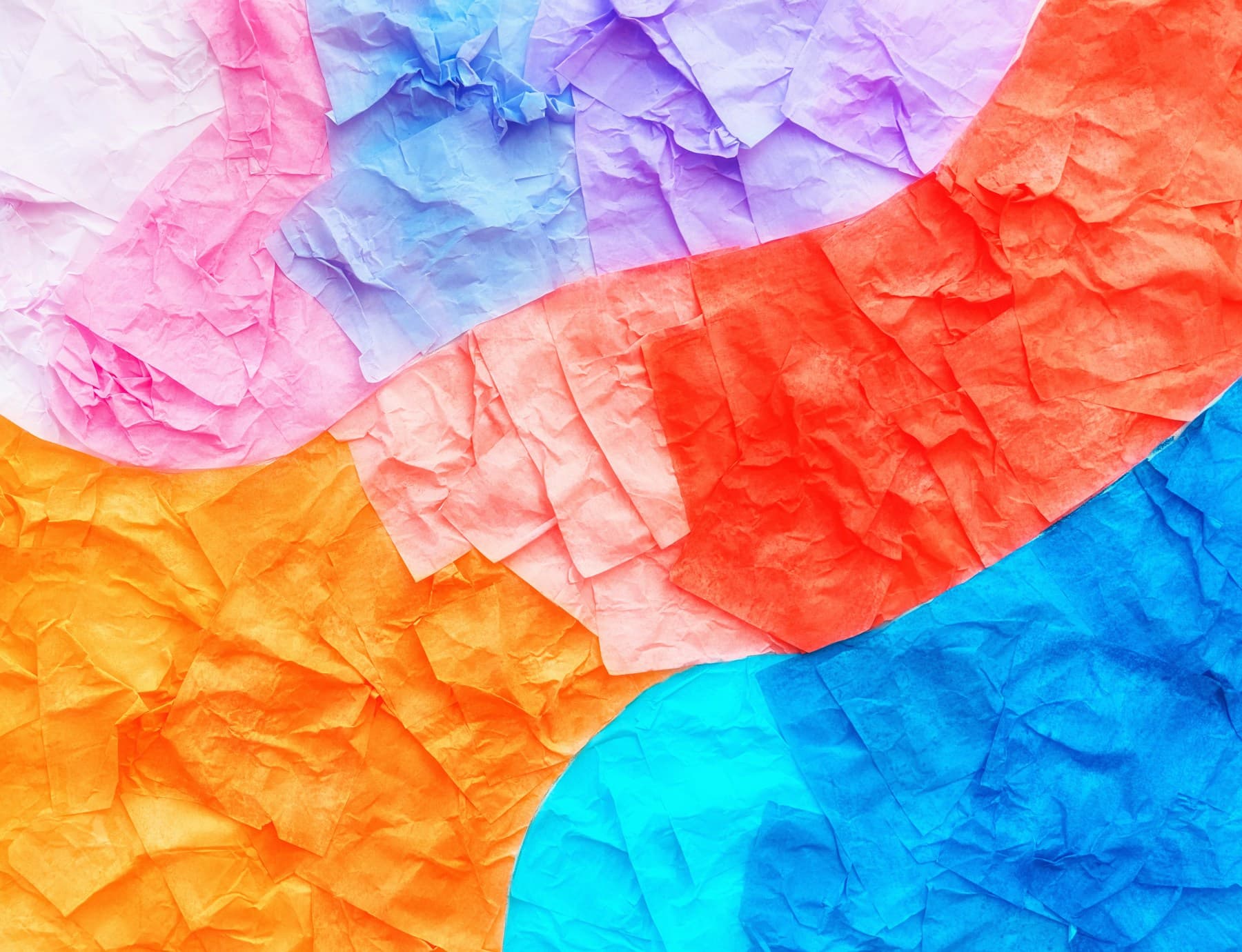 Crumpled multicolored paper with folds catching the light.